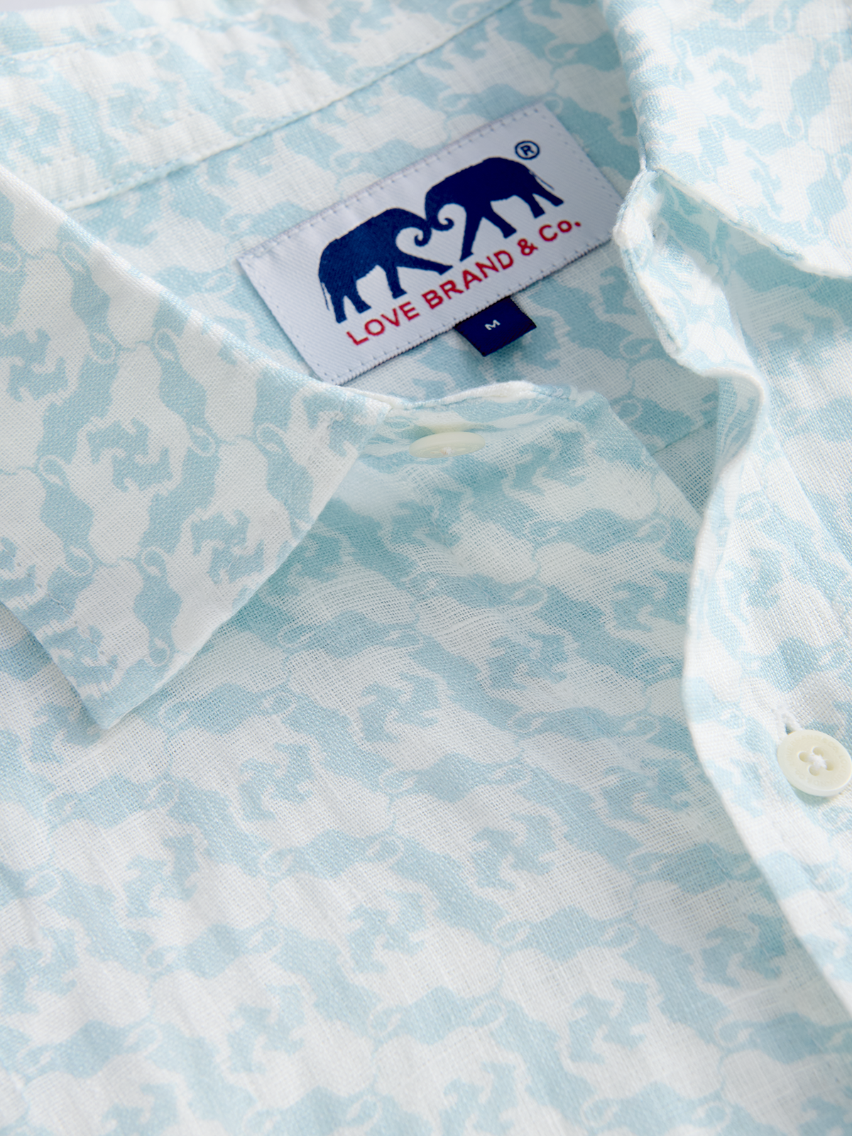 Close-up of a light blue patterned shirt with a love brand label on a white background