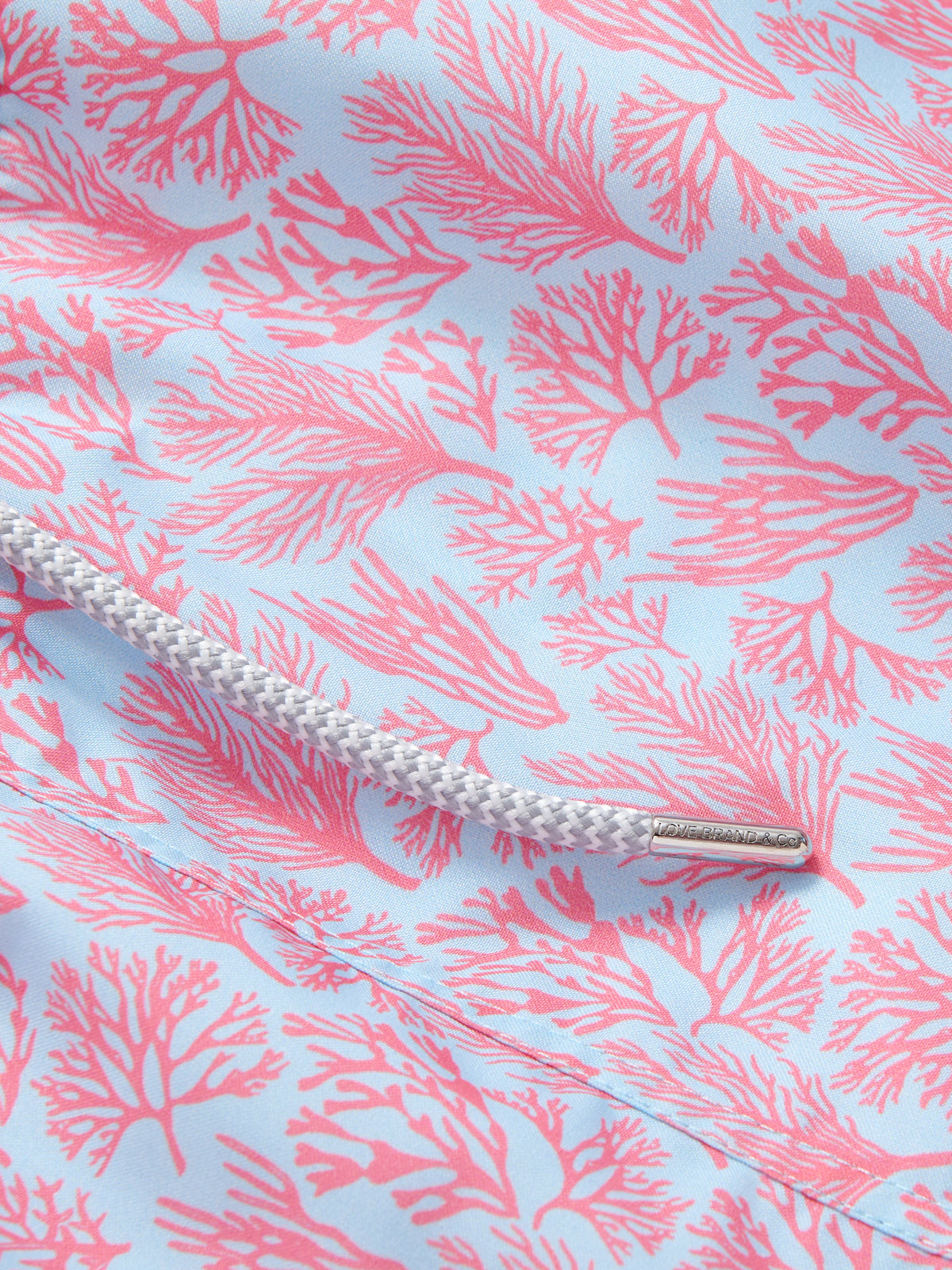 Detailed view of Boys Crazy Coral Staniel Swim Shorts. Infant swimwear featuring a blue and pink coral design with drawstring waist.