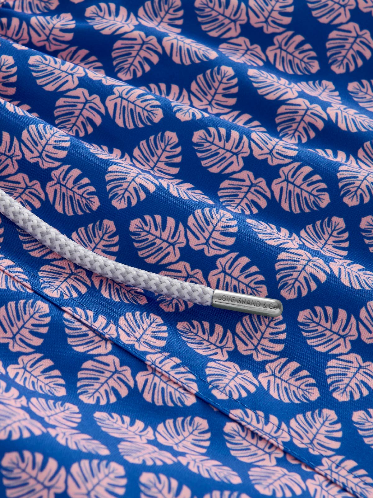 Blue fabric close-up with pink leaf pattern and drawstring.
