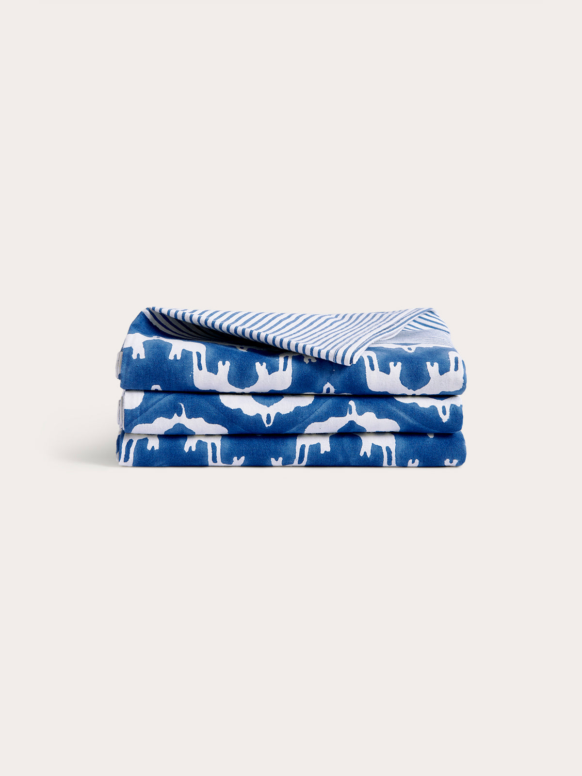 Folded cotton tablecloth featuring a blue and white Elephant Palace print with an elephant block-printed stripe on the edge.