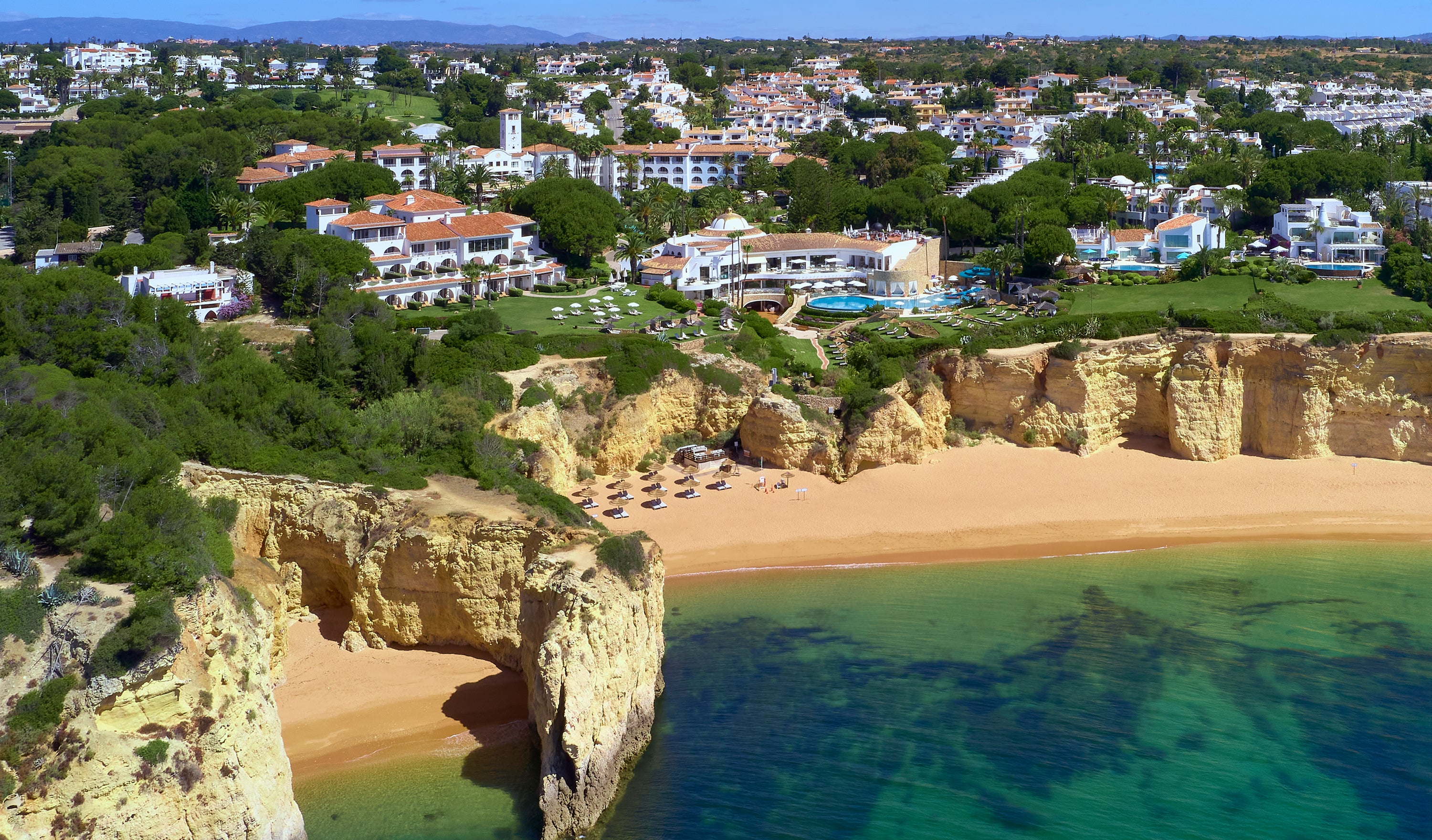 Aerial view of Vila Vita Resort with cliffs, beach, and clear blue water.