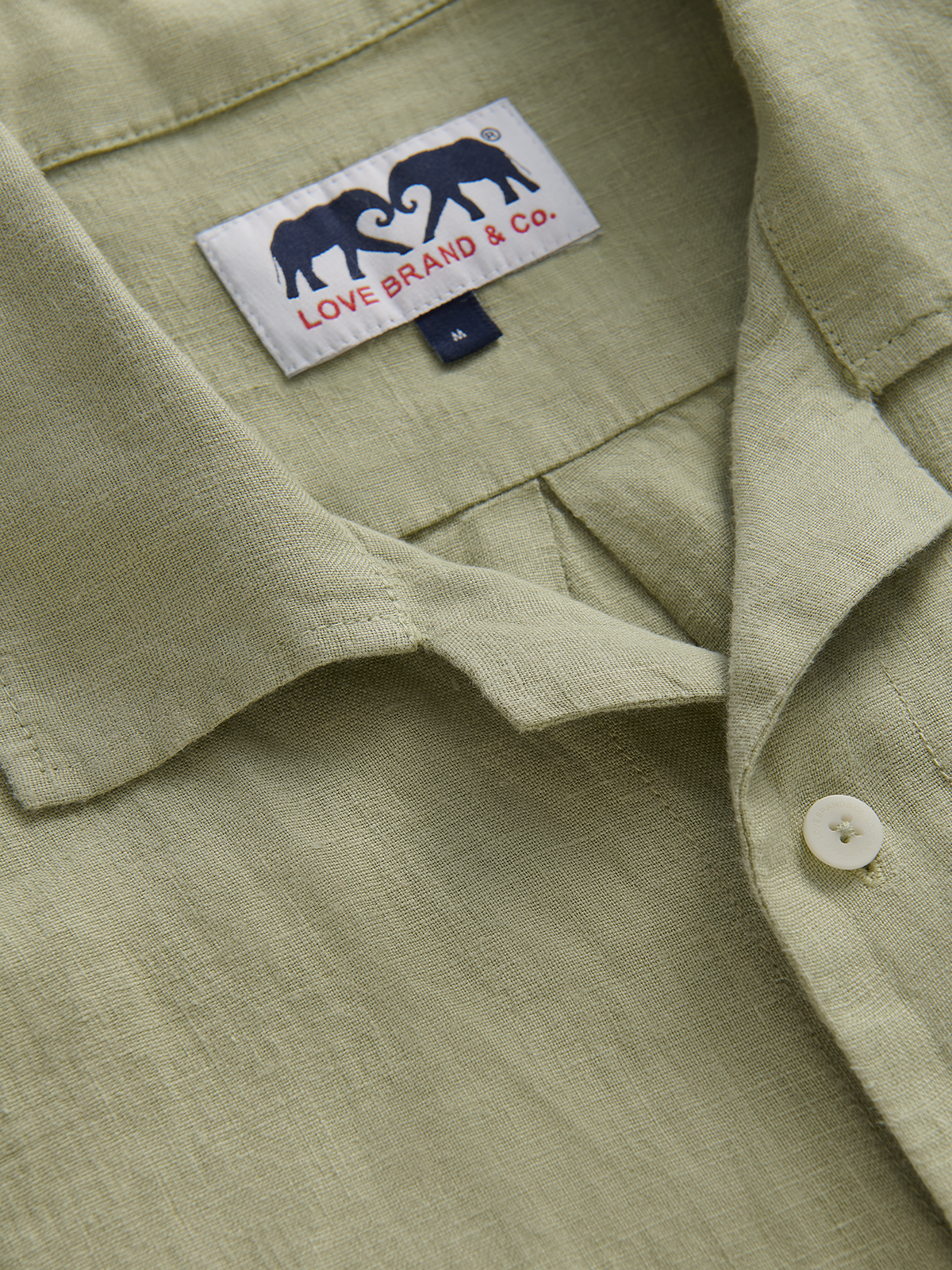 Collar view of mens green linen shirt featuring love brand label with two elephants