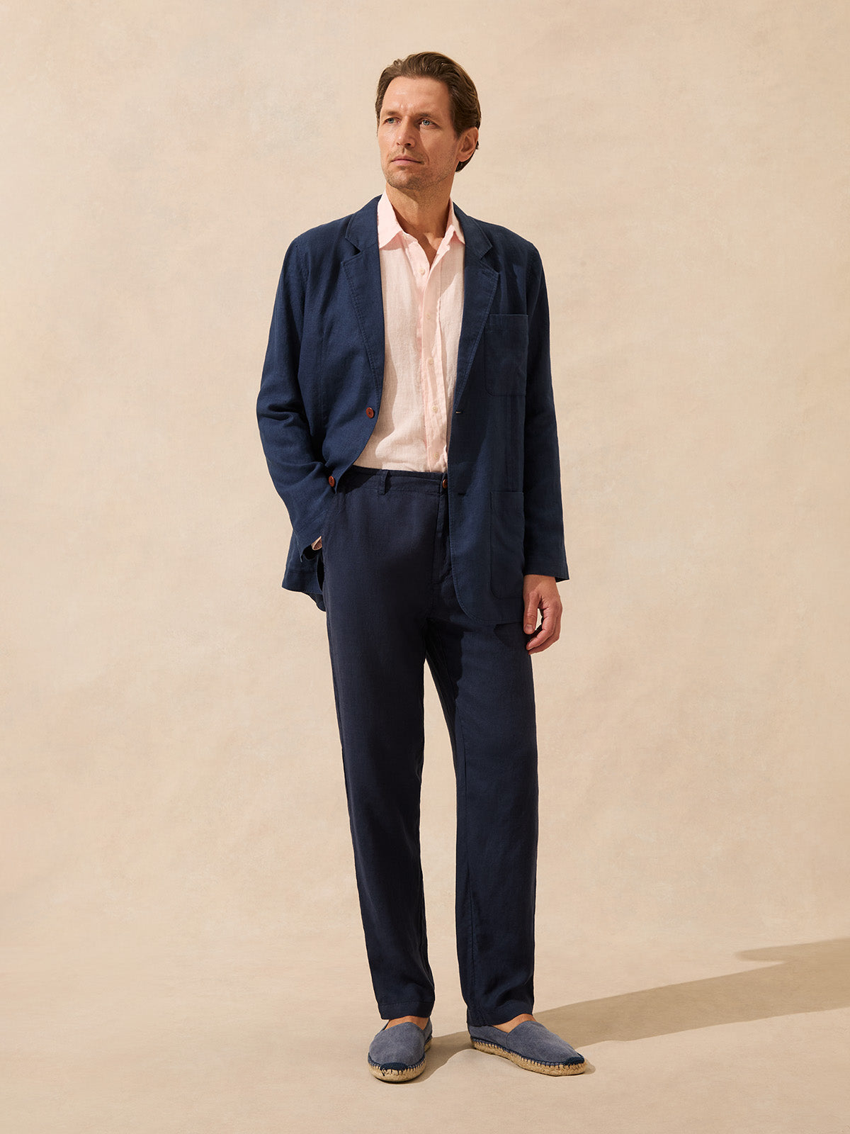 Man wearing a navy linen jacket, light pink shirt and navy linen trousers