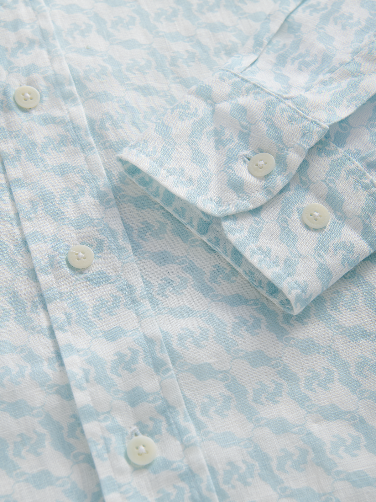Close-up of a light blue and white patterned shirt with buttons.