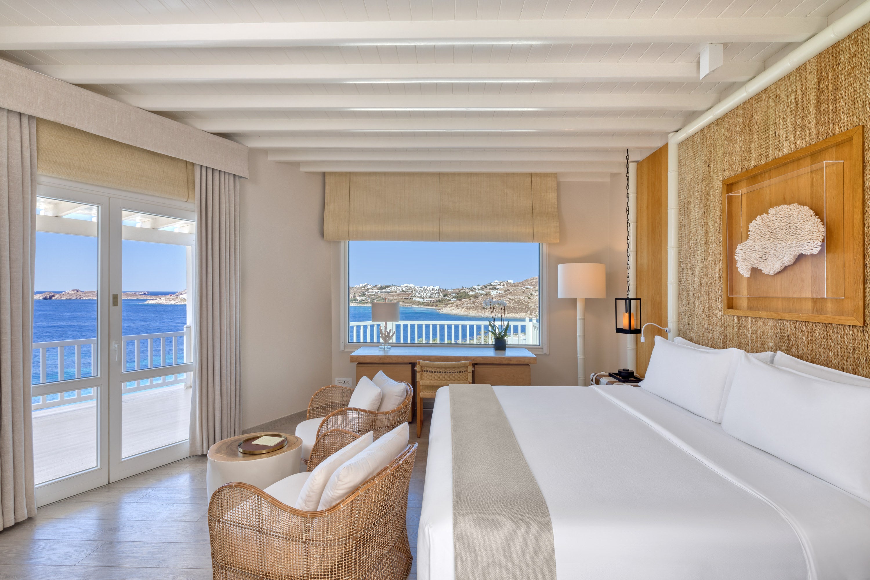 Luxury akro bedroom with ocean view, bed, chairs, and desk at Santa Marina.