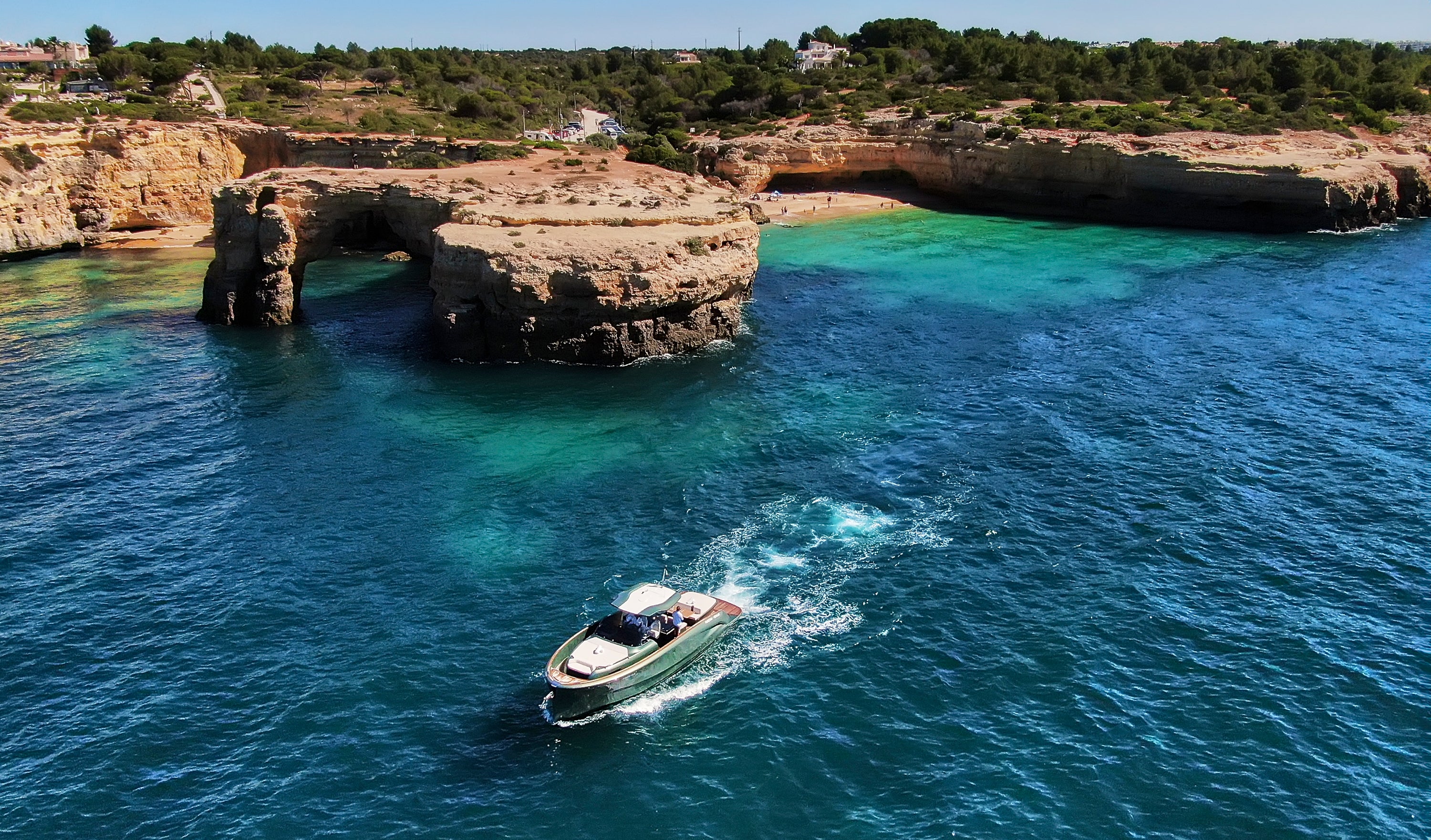 Boat navigating through turquoise waters near rocky cliffs
