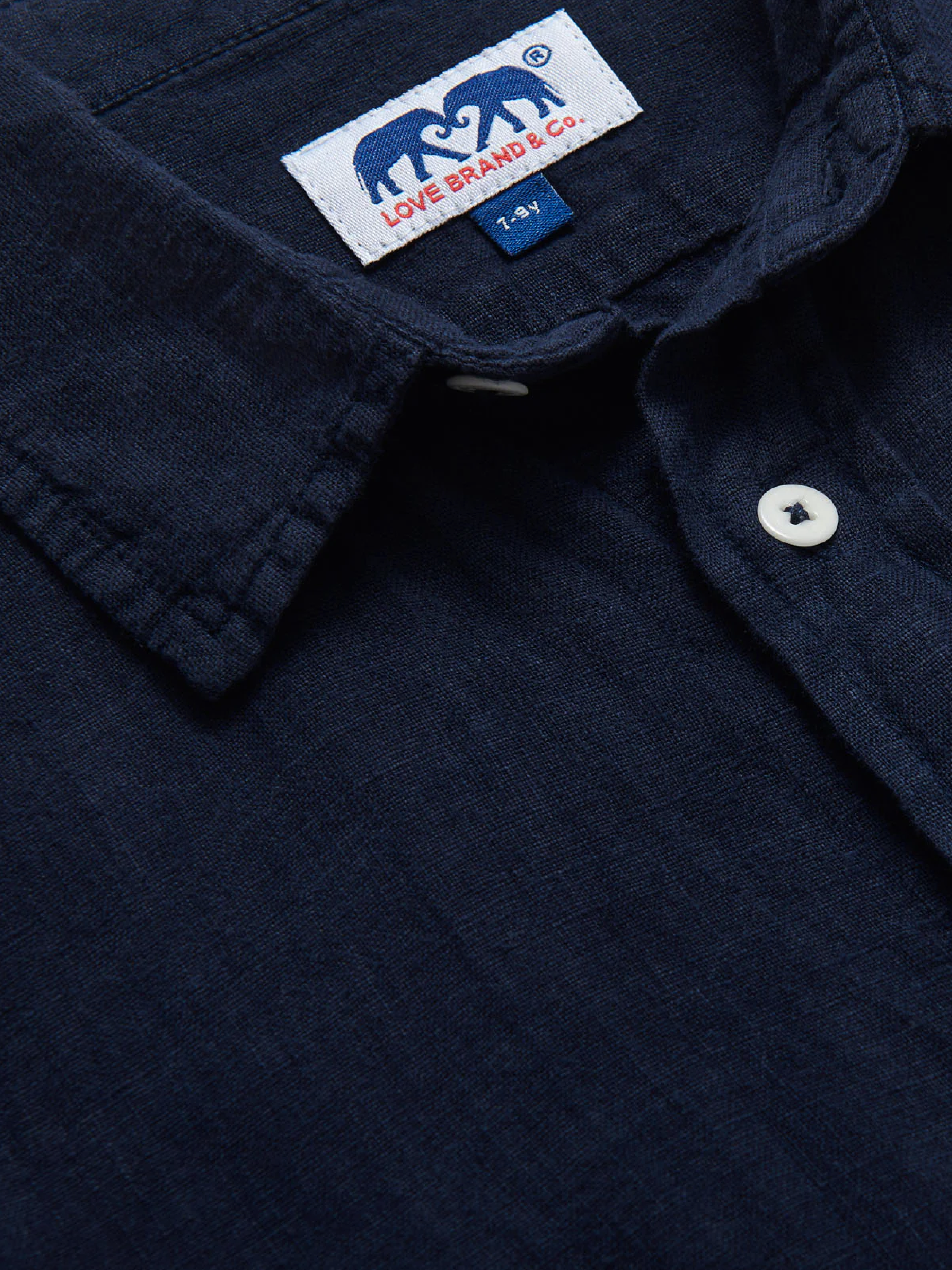 Close-up collar view of a kids navy blue linen shirt with a visible love brand label.