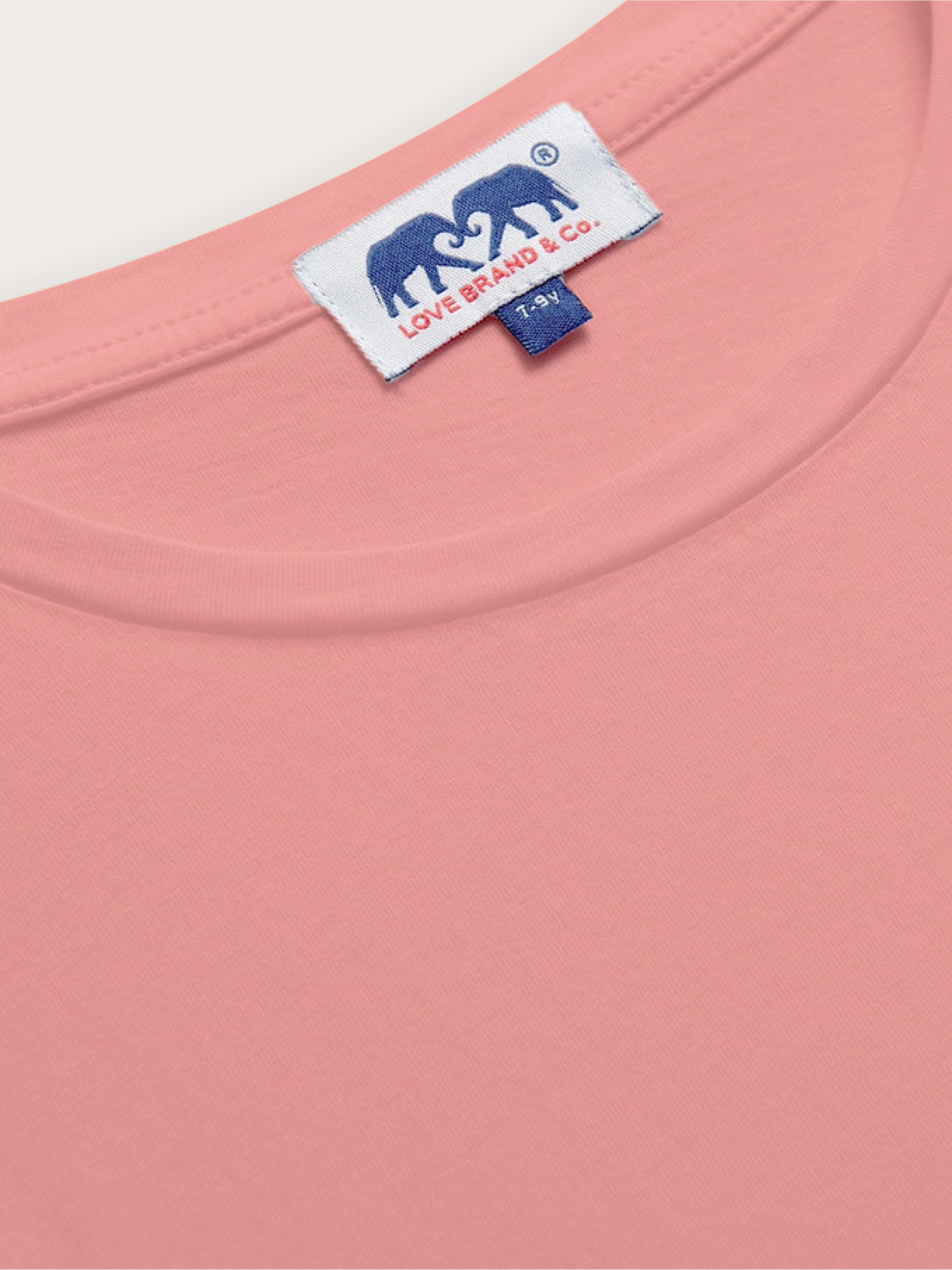 Close-up of a pink kids t-shirt with a brand label featuring an elephant logo.