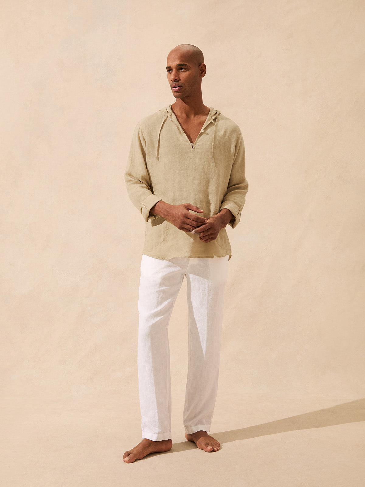 Man wears brown linen hoodie with white trousers