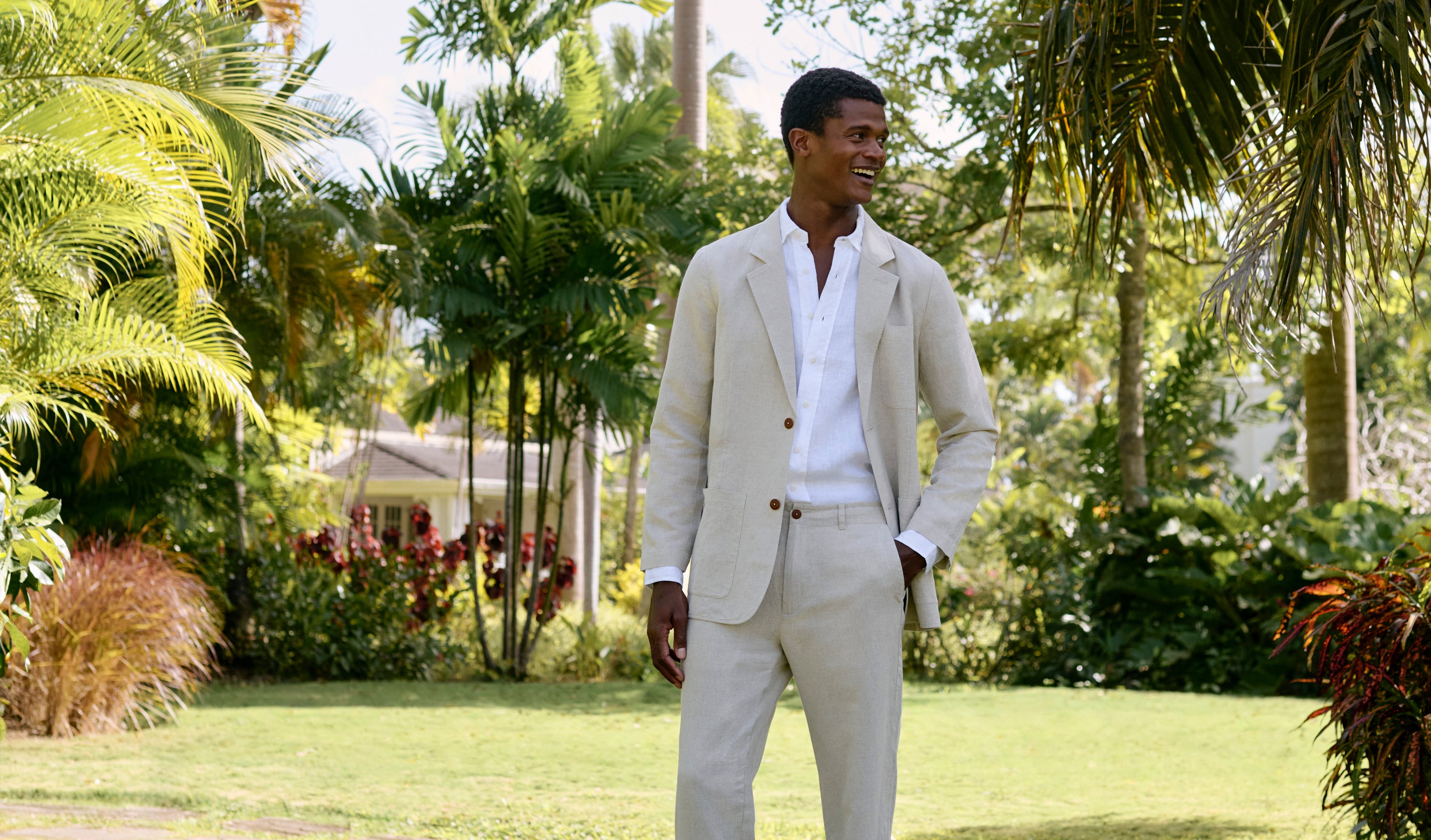 Man in a beige suit standing in a lush garden