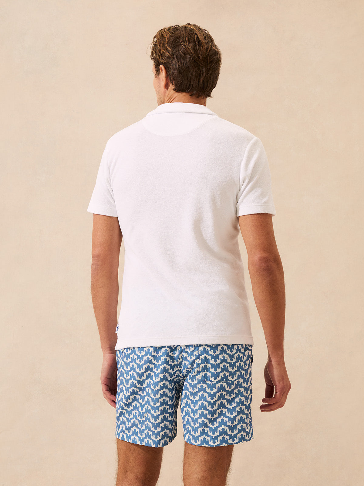 Back view of a man wearing a white terry polo shirt