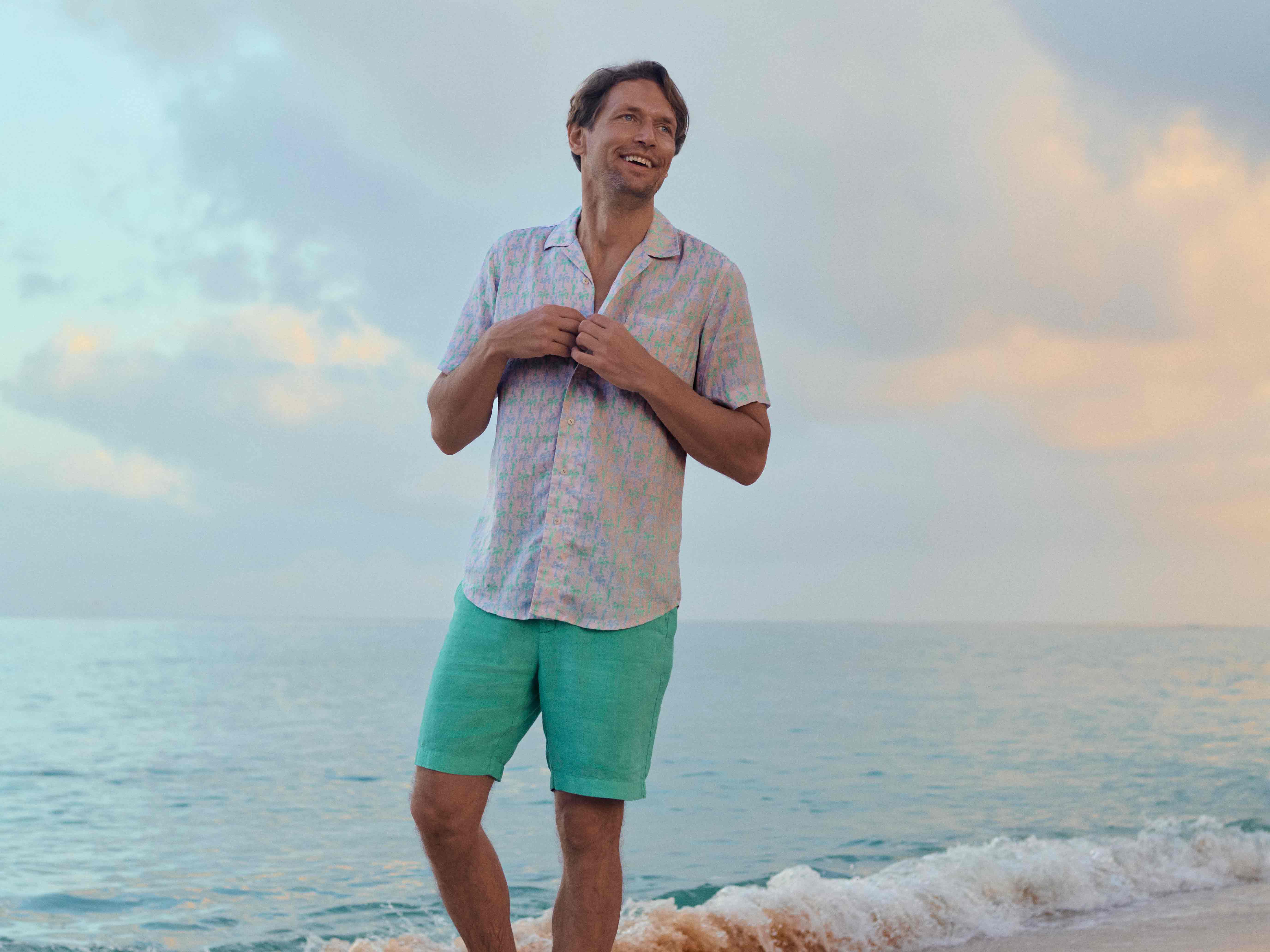 Man standing on a beach with ocean waves and sky in the background